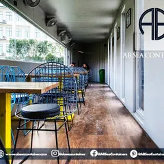 This cozy seating area within the cafe demonstrates efficient space planning. Large windows provide ample natural light and views of the surrounding landscape, making the narrow container feel open and airy.