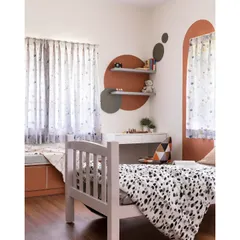 The colors of childhood come alive in this room designed for twins. The space features a playful mix of geometric shapes and an earthy orange color block, with a cozy window seat for reading or relaxing.