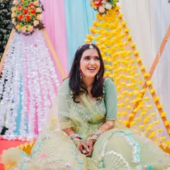 A radiant, smiling portrait of the bride during her Haldi ceremony, surrounded by beautiful floral decorations.