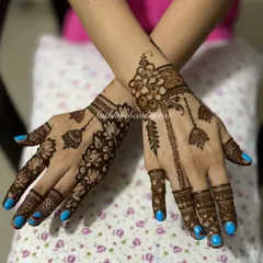 A beautiful jewelry-style mehndi with hanging jhumkas and lotus flowers. The blue nail polish makes the henna design stand out.