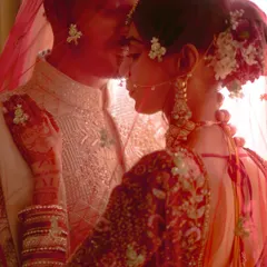 A moment of pure poetry. The bride and groom are captured through her red veil, a soft, intimate portrait that speaks of love and tradition.