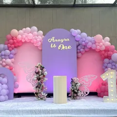 A beautiful butterfly theme for Anayra's first birthday. This outdoor setup uses a modern palette of pink and purple, with arch backdrops, floral arrangements, and delicate butterfly wing details.