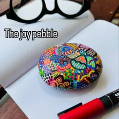 I call this one 'The joy pebble'. This hand-painted paperweight is a celebration of spontaneity and color therapy, perfect for brightening up your workspace.