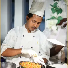 A chef at one of our live stations meticulously prepares a dish. His focus and precision reflect our team's dedication to delivering culinary excellence, one plate at a time.