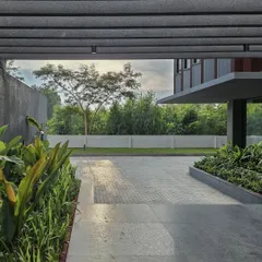 The view from the covered entrance walkway, looking out onto the landscaped grounds. The pergola structure frames the view, creating a deliberate and peaceful transition from the exterior to the interior.