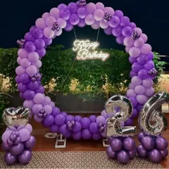 This outdoor setup features a full circle balloon arch in shades of purple. It's perfect for evening parties, with the neon 'Happy Birthday' sign and silver foil number balloons for the 26th birthday standing out against the night sky.