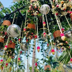 A daytime view of the fusion decor, where disco balls hang among fresh flowers, woven baskets, and coconut-shell tassels. This unique combination is perfect for a fun and stylish outdoor Mehendi or Haldi event.