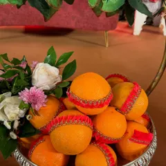 Even simple fruits can look luxurious. Here, a bowl of fresh oranges is decorated with red and gold lace, and topped with a small floral arrangement, elevating a simple offering into a beautiful gift.