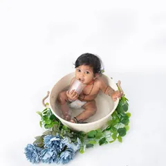 A simple and classic bathtub session against a clean white background. The focus is all on the baby's curious expression as he plays in the water, surrounded by a garland of blue flowers.