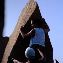 A climber ascends the iconic Left Arete on Rishimuk Plateau in Hampi. This shot captures the focus and strength required for such a beautiful and technical climb, with a spotter ensuring safety.