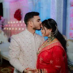 A tender moment between the bride and groom during their wedding reception, with the groom placing a gentle kiss on her forehead.