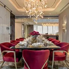 A dining room that makes a bold statement with its rich, red velvet chairs and a custom chandelier that resembles birds in flight. The dark marble table and gold accents create an atmosphere of pure opulence, perfect for formal entertaining.