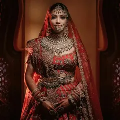 A full-length bridal portrait showcasing the magnificent red lehenga and intricate jewelry. We use careful lighting to make sure every detail of the bride's look is captured perfectly.