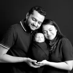 We believe these first family portraits are priceless. This classic black and white shot captures the pure love and connection between new parents and their sleeping baby, a memory to cherish forever.