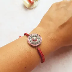 This sparkling Rakhi is perfect for adding a bit of glam to the traditional ceremony. The center is filled with crystals and it's tied with a classic red braided thread.