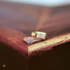 A detailed close-up of the bride and groom's engagement rings resting on a wooden surface. This macro shot highlights the beautiful design and sparkle of the rings that mark their commitment.
