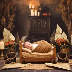 A warm and rustic newborn scene. The baby sleeps peacefully in a tiny wooden bed, surrounded by candles, pinecones, and dried botanicals for a cabin-like feel.
