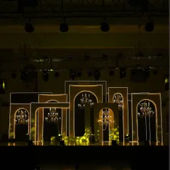 The Sangeet stage, set with dramatic silhouettes and shimmering chandeliers. The multi-layered arch backdrop was designed to create depth and a sense of grandeur for the performances.