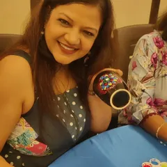 Another happy participant from the ladies' group get-together. The close-up shows the intricate and vibrant dot pattern she created on her black ceramic mug, a functional piece of art she can use every day.