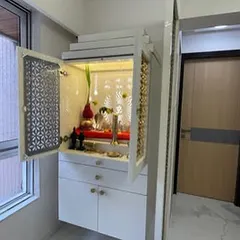 Another elegant mandir design, this one in white with delicate jali work, placed near a window to fill the space with natural light.