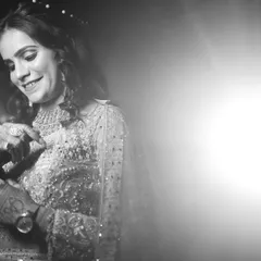 A black and white version of a candid bridal moment. The lack of color emphasizes her joyful expression and the beautiful textures of her sparkling dress and jewelry.