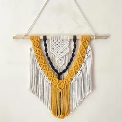 This custom-ordered, three-layered macrame wall hanging showcases our intricate knotting work. We combined off-white, black, and mustard yellow threads to create a striking boho design that adds texture and personality to any wall.