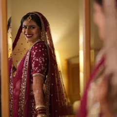 A classic bridal portrait, with the bride looking at her reflection in the mirror, capturing a moment of quiet anticipation.