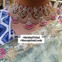 A client trying on a beautiful diamond-look choker with ruby and emerald accents. This is a perfect choice for a reception or cocktail party.