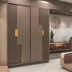 This wardrobe design combines function with artistry. The sliding doors feature a unique geometric pattern with fluted textures and metallic gold accents, turning a storage unit into a statement piece.