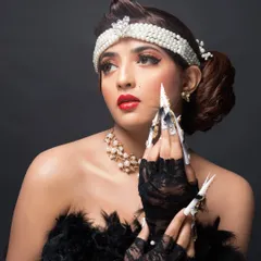 A close-up of the model's hands, highlighting the showstopping fantasy nail art and its glamorous, over-the-top style.