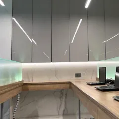 A custom-designed work corner in the advocate's office, featuring sleek overhead storage, under-cabinet lighting, and a clean, minimalist aesthetic. The marble flooring continues throughout the space for a cohesive look.