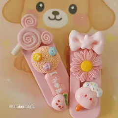 Pretty in pink! This handmade hair clip is loaded with sweet charms like a cookie, a flower, and a little ice cream cone. It’s a perfect example of the detailed, cute accessories I love to create.