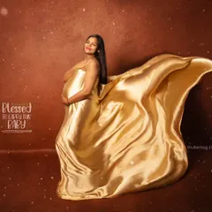 A truly glamorous maternity portrait featuring a solo mom-to-be. The flowing golden satin fabric creates a sense of movement and elegance, making for a dramatic and unforgettable fine-art pregnancy photo.