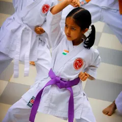 A young student demonstrates a powerful high block during an outdoor training session. Her focused expression and sharp form showcase the discipline and technical skill we instill in our karateka from an early age, building both physical strength and mental concentration.