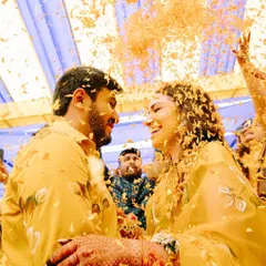 A 'phoolon ki holi' moment at a Haldi ceremony. The air filled with flower petals, and the couple sharing a look of pure joy, this is what celebrations are all about.