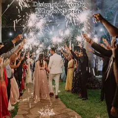 A beautiful shot of the couple walking through a path lit by sparklers held by their loved ones, creating a warm and celebratory welcome.