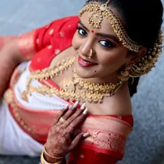 A beautiful high-angle shot of a South Indian bride in her traditional red and white saree. This perspective highlights the stunning temple jewelry and the elegance of the moment.