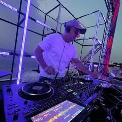 Setting the vibe for a sundowner wedding event. This shot captures me in my element, mixing tracks on my Pioneer DJ setup against a beautiful sunset, with a custom lighting rig ready for the night ahead.