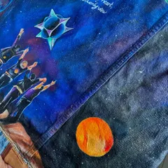 A detailed shot focusing on the hand-lettered lyrics and the celestial bodies painted on the jacket. The fine white script stands out against the deep blue and purple nebula, and the small orange planet adds a pop of color.