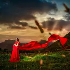 This dramatic red trail gown isn't just for pre-weddings; it's also a stunning choice for a powerful and beautiful maternity shoot. The flowing fabric creates a breathtaking silhouette against a natural landscape.