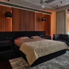 A bedroom that masterfully blends textures and tones. The warm wood paneling behind the bed, combined with soft backlighting, creates a cozy and inviting ambiance, perfect for a restful escape.