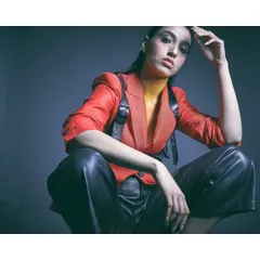 This look combines a bold red blazer with sleek black leather pants and a harness. The styling creates a powerful, edgy aesthetic, using color and texture to convey strength and confidence.