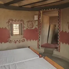 This bedroom shows the beauty of vernacular design, with its patterned mud-plastered walls, exposed ceiling beams, and deep-set windows. These traditional techniques naturally keep the interiors cool and comfortable.