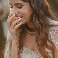 A candid close-up of the bride's happy and shy smile during her mehndi ceremony.