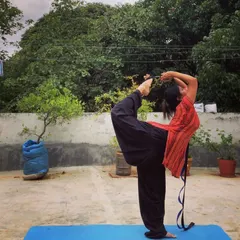 Practicing Natarajasana (Dancer's Pose) on my terrace with a strap. The strap helps me get a better grip and deepen the backbend without compromising my alignment.