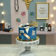 A special cake for a healthcare hero. This design replicates a doctor's scrubs, complete with a fondant stethoscope, pills, a syringe, and a band-aid. It's a sweet prescription for a happy birthday.