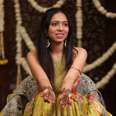 The bride showing her beautiful mehendi design. The decor behind her, with jasmine garlands and a carved wooden screen, was designed to create a traditional and elegant backdrop.