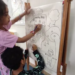 Teamwork makes the dream work! Two children collaborate on their large-scale drawing, discussing their ideas and sharing the creative process.
