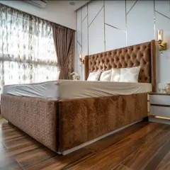 This bedroom features a stunning tufted wingback headboard in a rich brown velvet. I paired it with a geometric-paneled accent wall and warm bedside sconces to create a space that feels both grand and incredibly cozy.