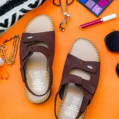 A colorful flatlay of brown orthopedic sandals surrounded by makeup and accessories. The bright orange background makes this image stand out in a crowded feed.